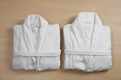 Photo of Clean folded bathrobes on wooden background, flat lay