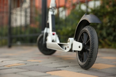 Photo of Modern electric kick scooter on city street, closeup