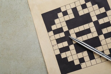Photo of Blank crossword and pen on old white table, top view. Space for text