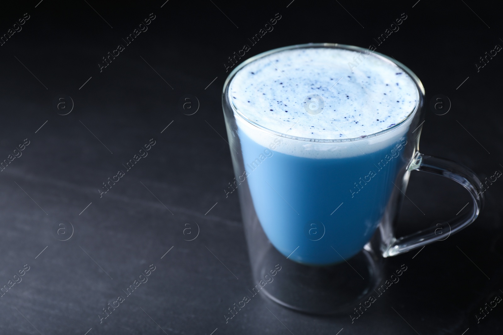 Photo of Delicious blue matcha latte on black table. Space for text