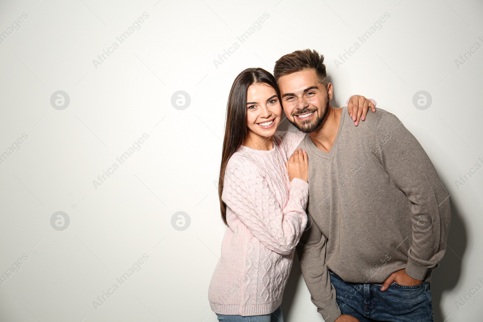 Image of Lovely couple in warm sweaters on light background. Space for text