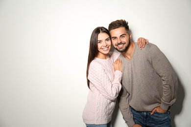 Image of Lovely couple in warm sweaters on light background. Space for text