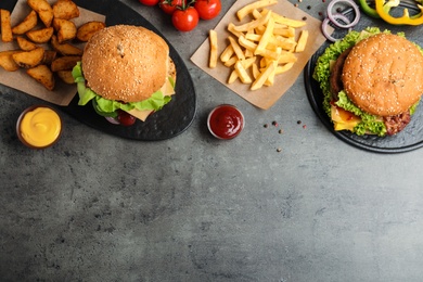 Photo of Flat lay composition with tasty burgers and french fries on table. Space for text