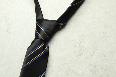 Photo of One striped necktie on light textured table, top view. Space for text