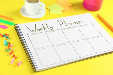 Photo of Composition of notebook with weekly plan on yellow background