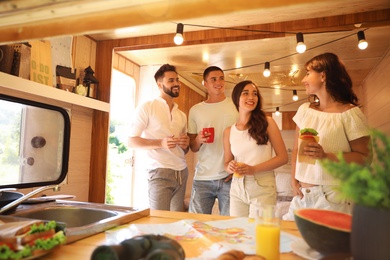 Photo of Happy young people having breakfast in trailer. Camping vacation