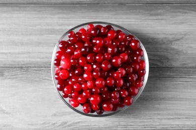 Photo of Fresh ripe cranberries in bowl on grey wooden table, top view