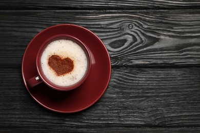 Photo of Cup of aromatic coffee with heart shaped decoration on black wooden table, top view. Space for text