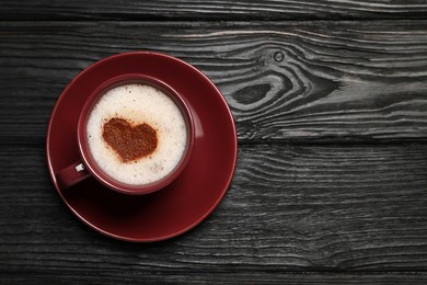 Cup of aromatic coffee with heart shaped decoration on black wooden table, top view. Space for text