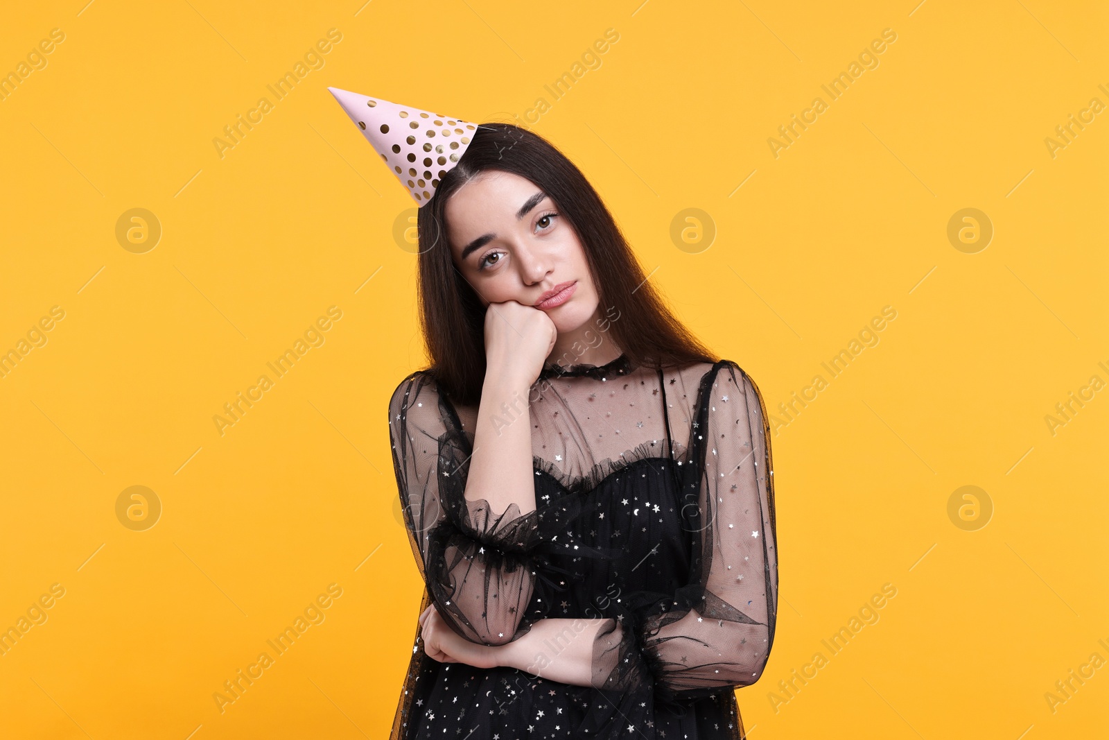 Photo of Sad woman in party hat on orange background