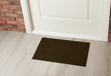 Dark olive door mat on wooden floor in hall