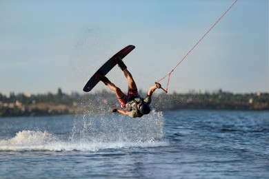 Photo of Teenage wakeboarder doing trick over river. Extreme water sport