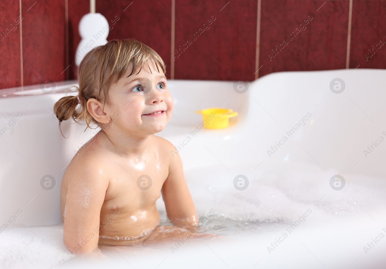 Photo of Smiling girl bathing in tub at home, space for text