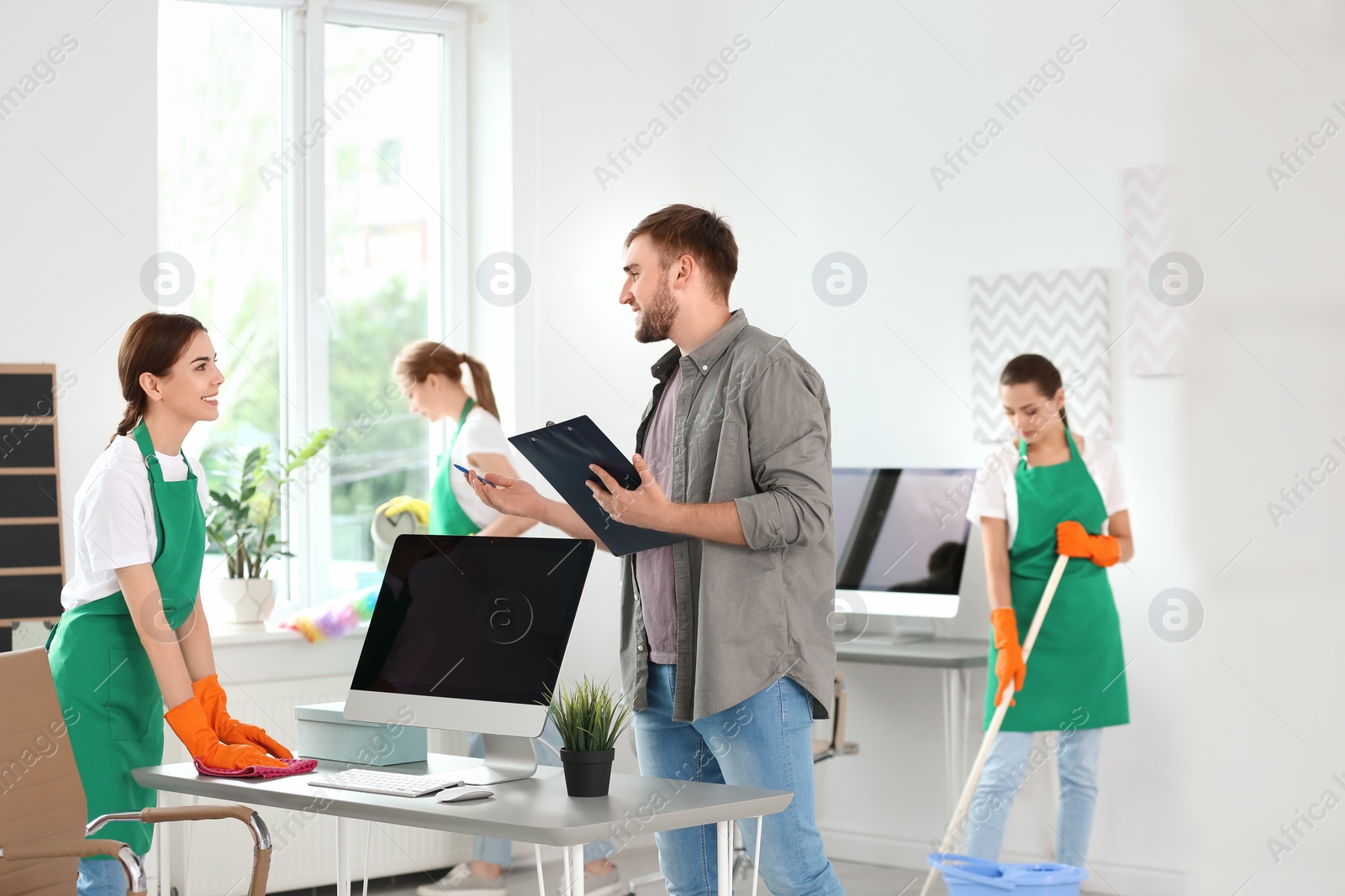 Photo of Team of professional janitors in uniform cleaning office