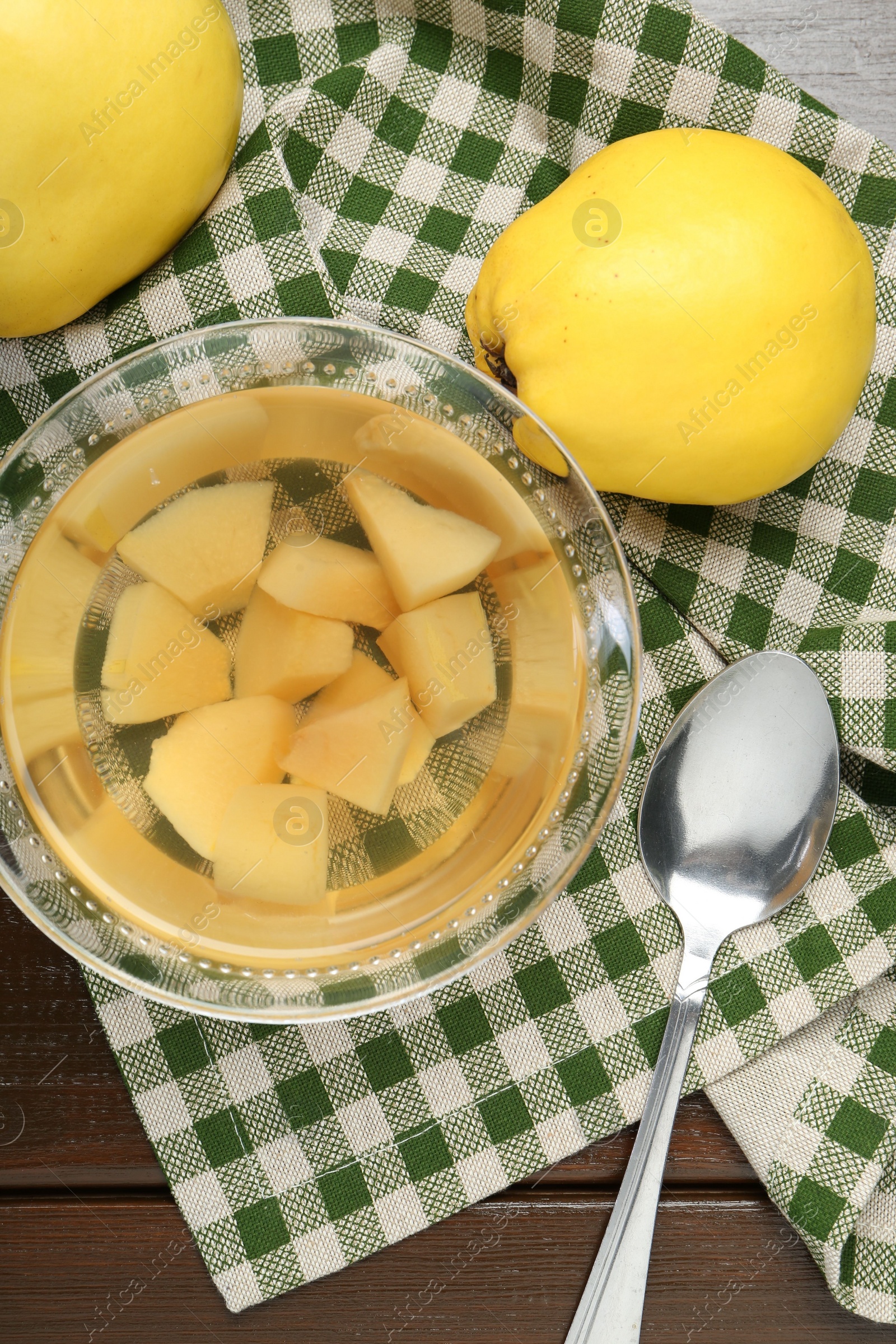 Photo of Delicious quince drink in glass bowl, fresh fruits and spoon on wooden table, top view