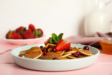 Cereal pancakes with berries on pink wooden table