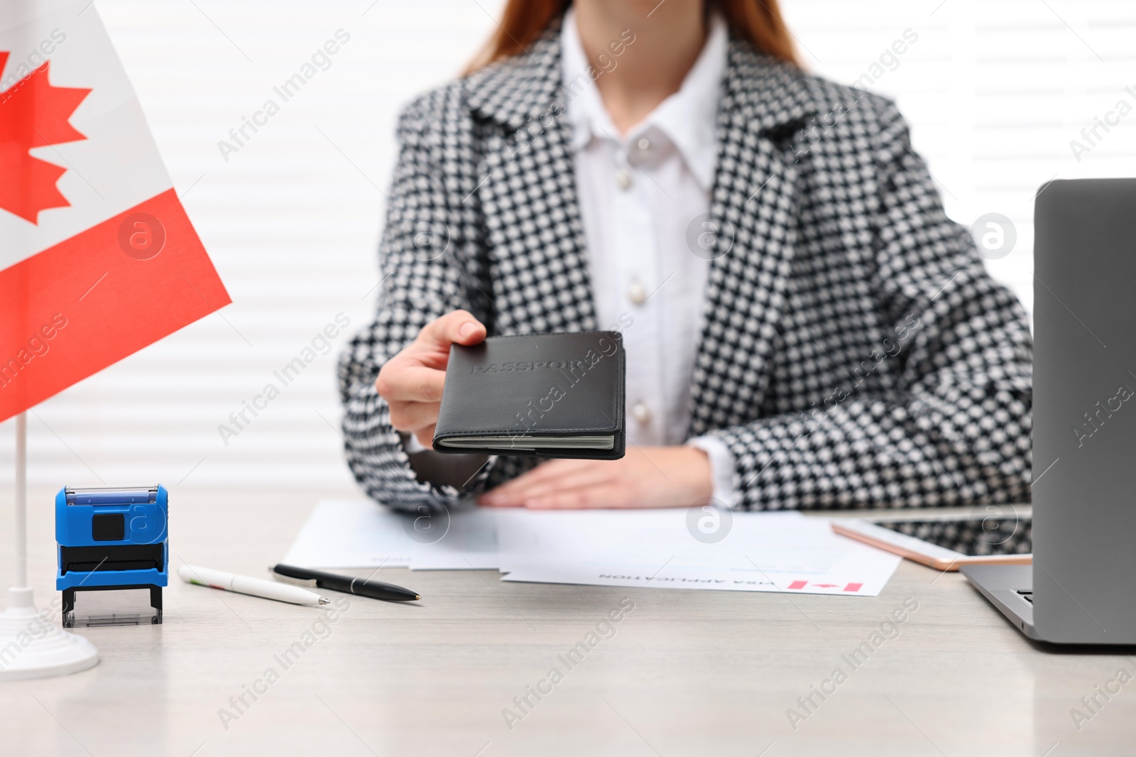 Photo of Immigration to Canada. Embassy worker with passport and documents at table in office, closeup