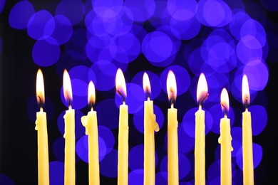 Hanukkah celebration. Burning candles against dark background with blurred lights, closeup