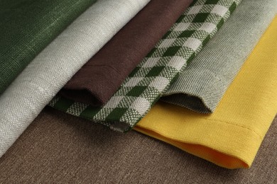 Photo of Many different fabrics on brown cloth, closeup