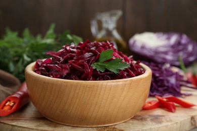 Photo of Tasty red cabbage sauerkraut with parsley on wooden table, closeup