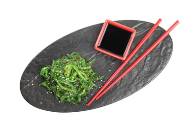 Photo of Slate plate with Japanese seaweed salad, soy sauce and chopsticks isolated on white, top view