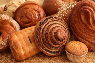 Photo of Different tasty freshly baked pastries on wicker mat, closeup