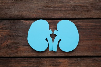 Paper cutout of kidneys on wooden table, top view