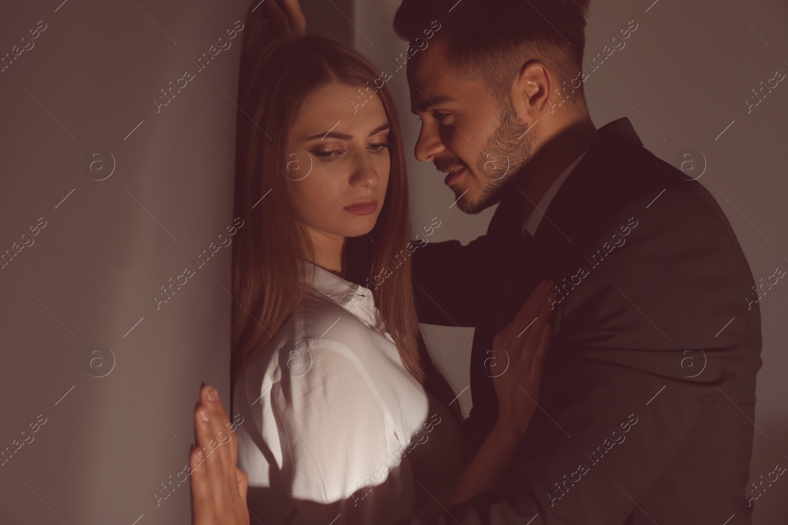 Photo of Boss molesting his female secretary on dark background. Sexual harassment at work