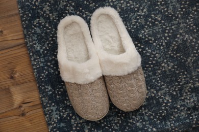 Photo of Pair of beautiful soft slippers and rug on wooden floor, top view