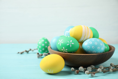 Photo of Colorful Easter eggs on light blue wooden table against white background. Space for text