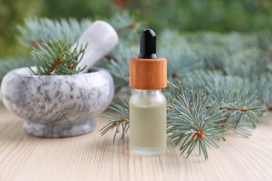 Pine essential oil and branches on white wooden table, closeup