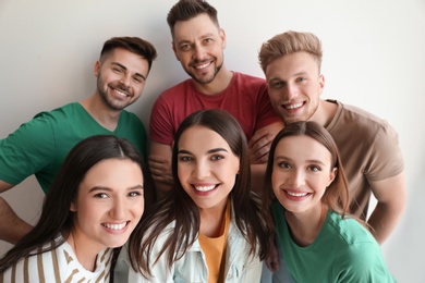 Photo of Group of happy people posing near light wall