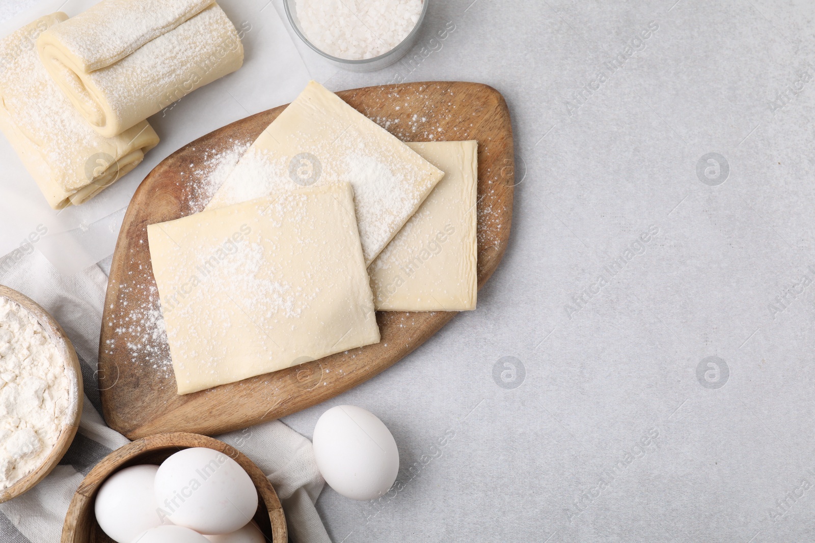 Photo of Raw puff pastry dough and ingredients on white table, flat lay. Space for text