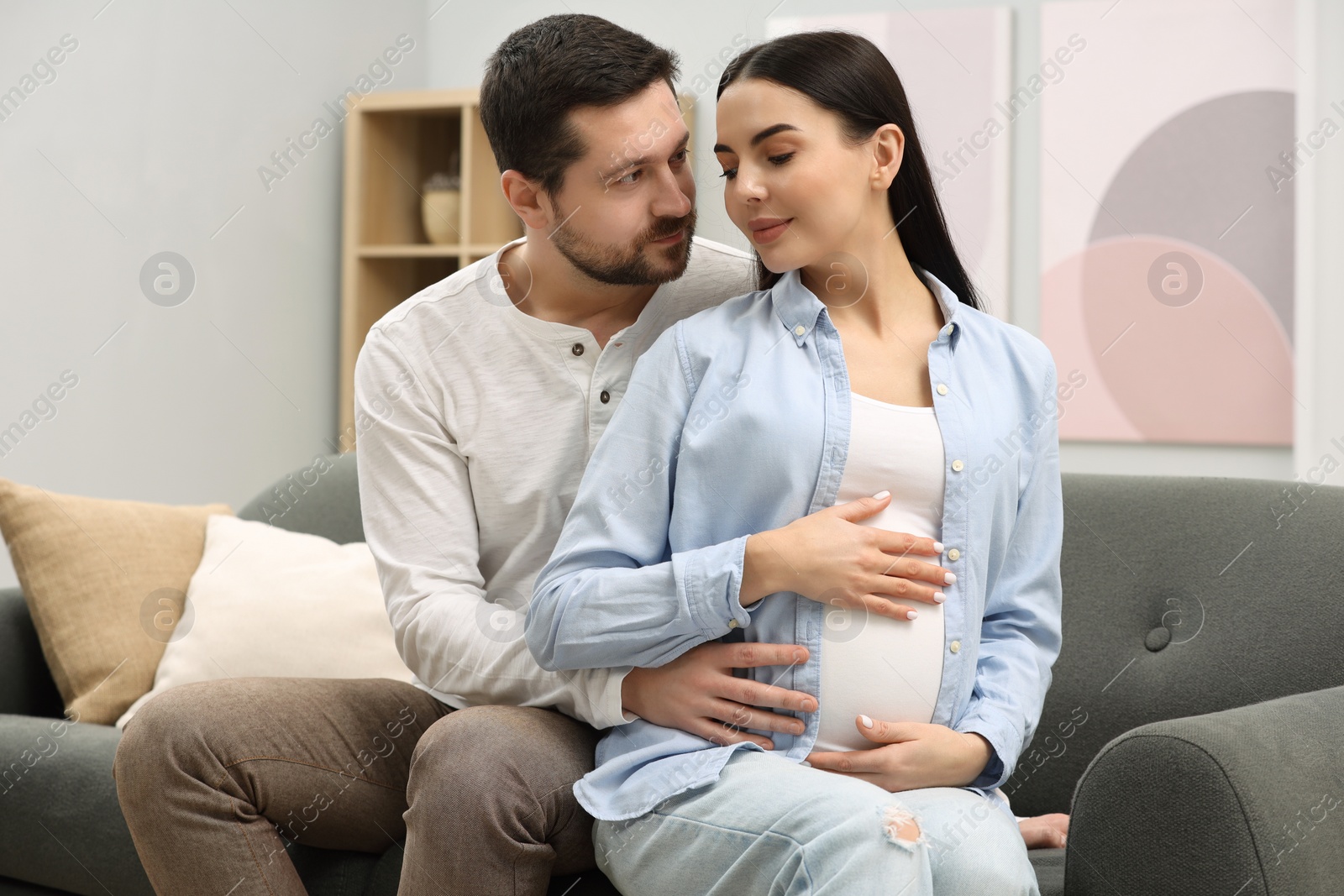 Photo of Pregnant woman with her husband on sofa at home