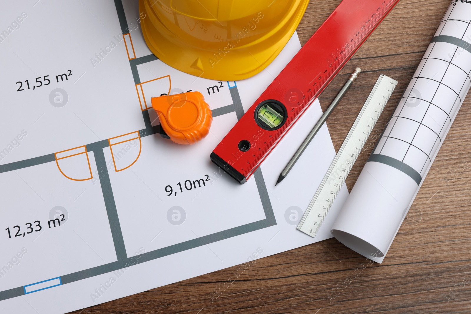 Photo of Construction drawings, safety hat, tape measure and bubble level on wooden table, flat lay