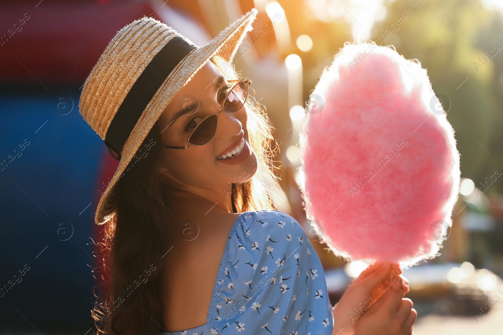 Photo of Beautiful young woman with cotton candy outdoors on sunny day