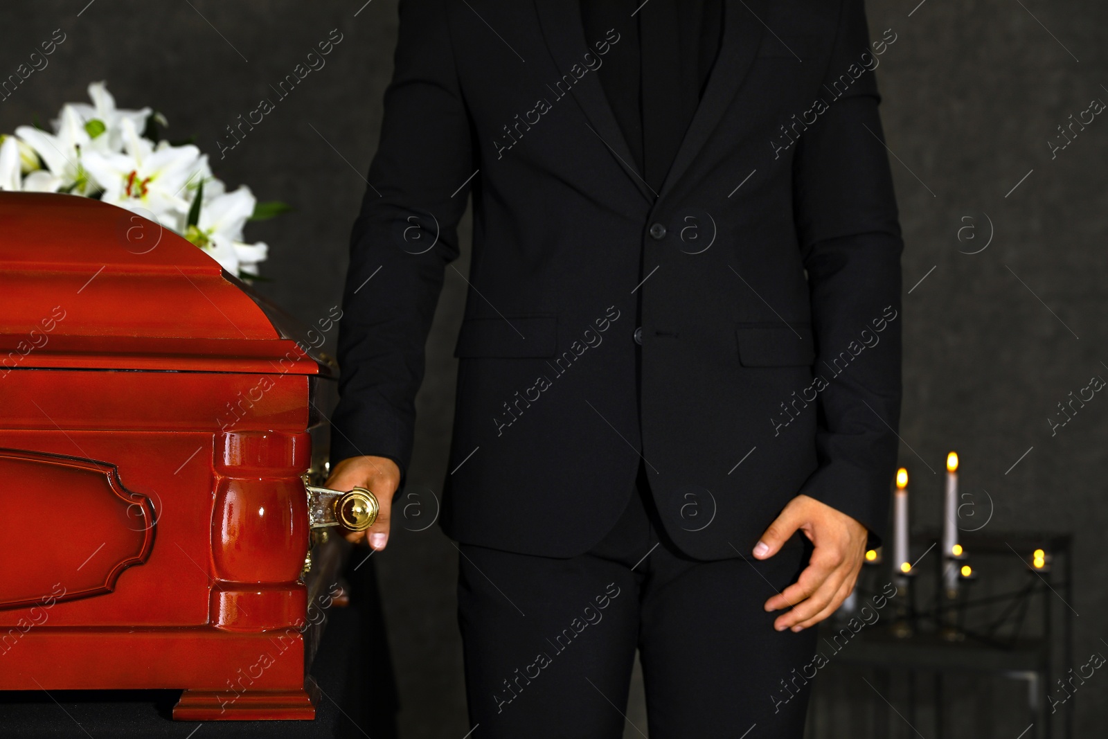 Photo of Young man carrying wooden casket in funeral home, closeup