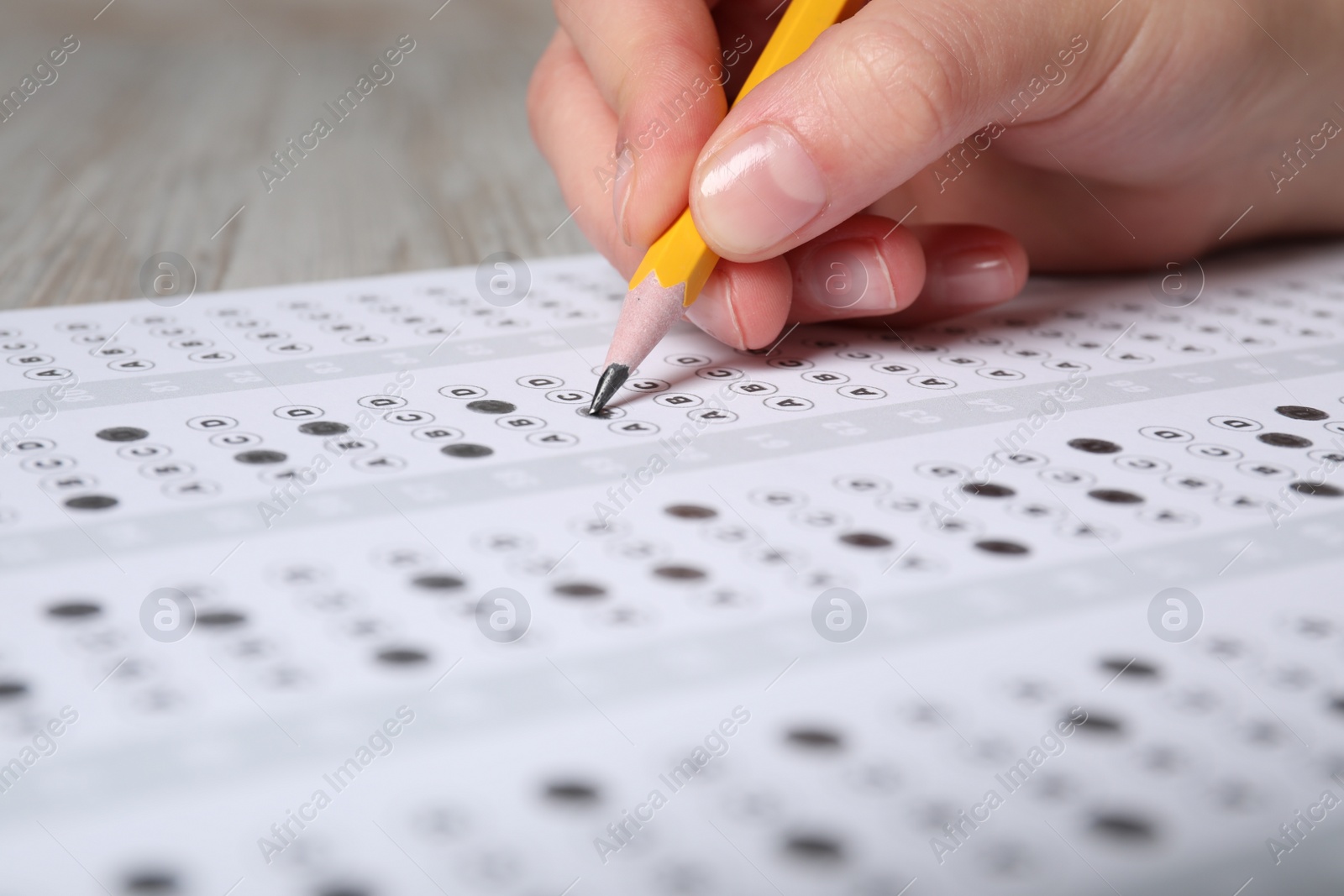 Photo of Student filling answer sheet at table, closeup. Passing exam