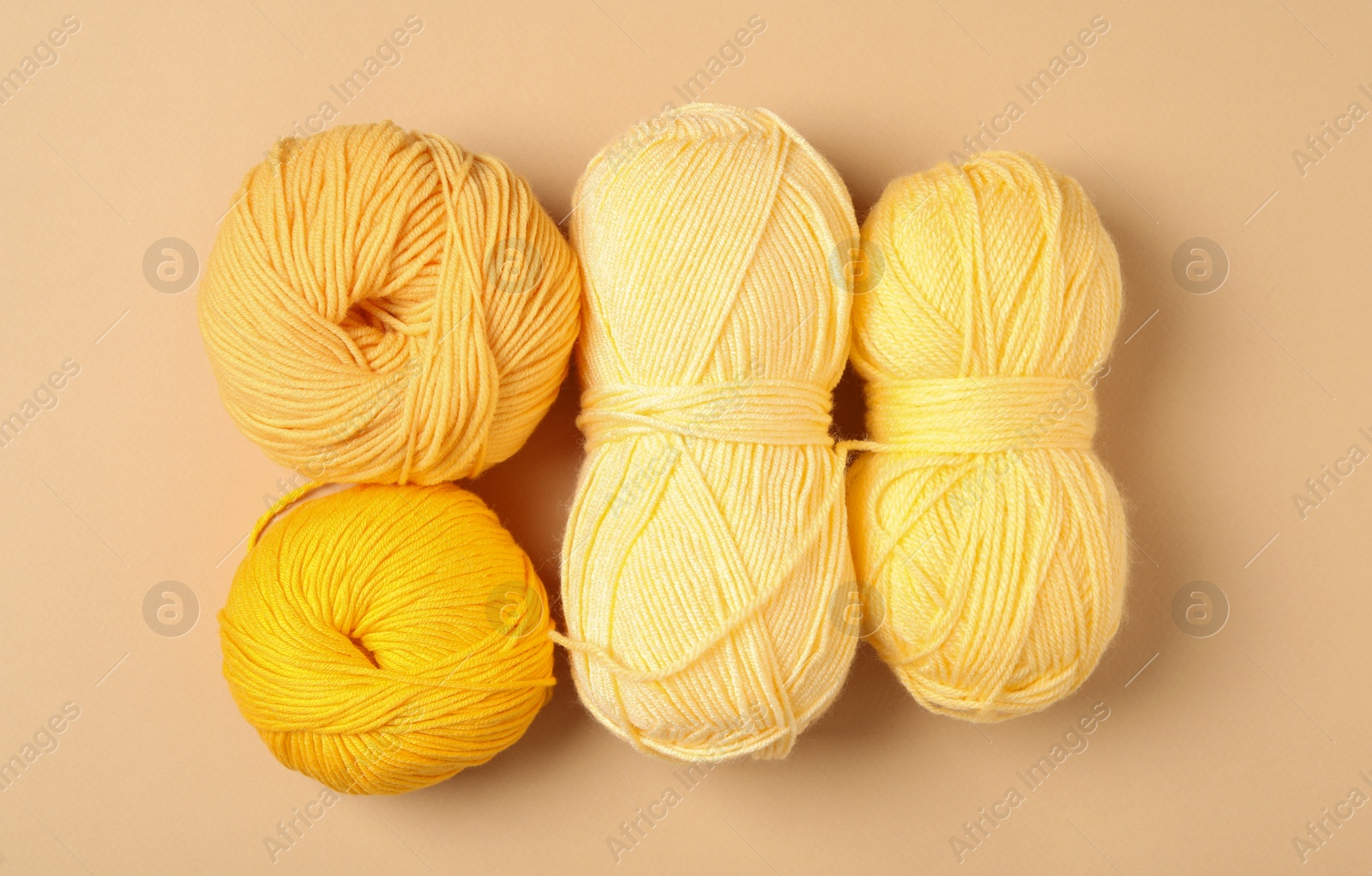 Photo of Soft woolen yarns on beige background, flat lay