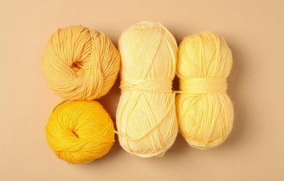 Photo of Soft woolen yarns on beige background, flat lay