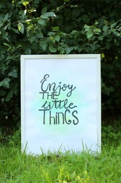 Poster with phrase Enjoy The Little Things on grass outdoors