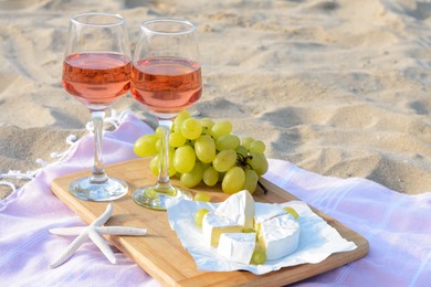 Glasses with rose wine and snacks for beach picnic on sand outdoors