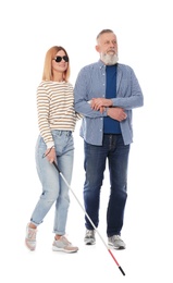 Mature man helping blind person with long cane on white background