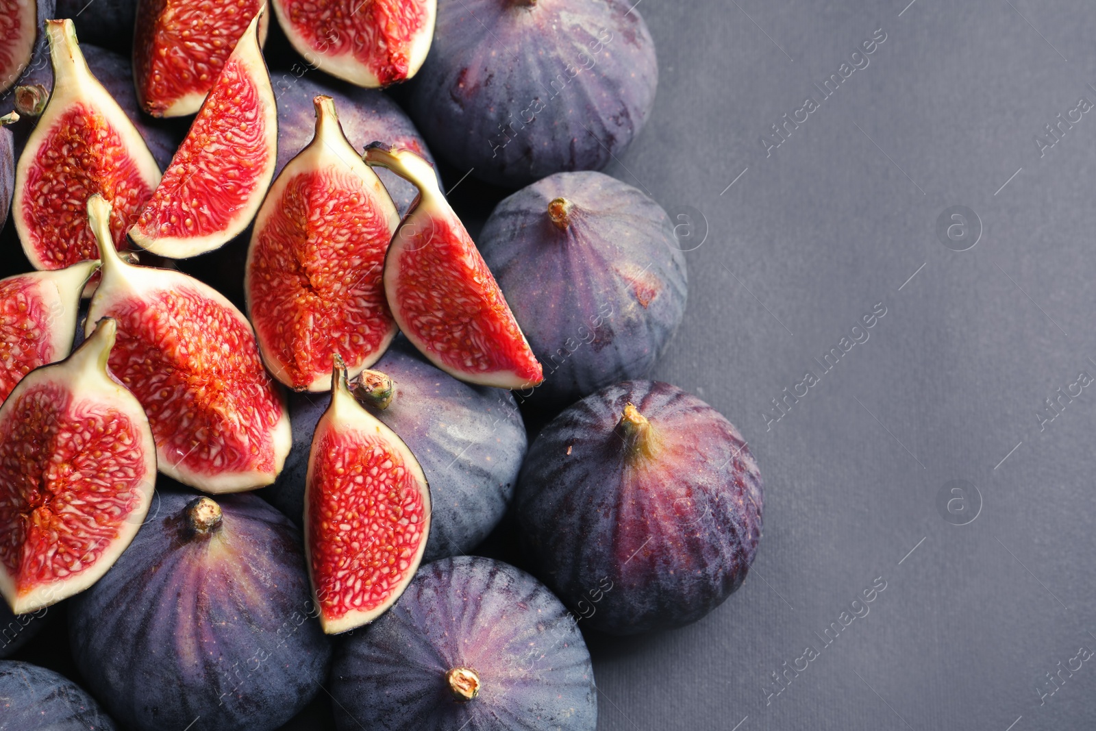 Photo of Fresh ripe figs on gray background, top view. Space for text