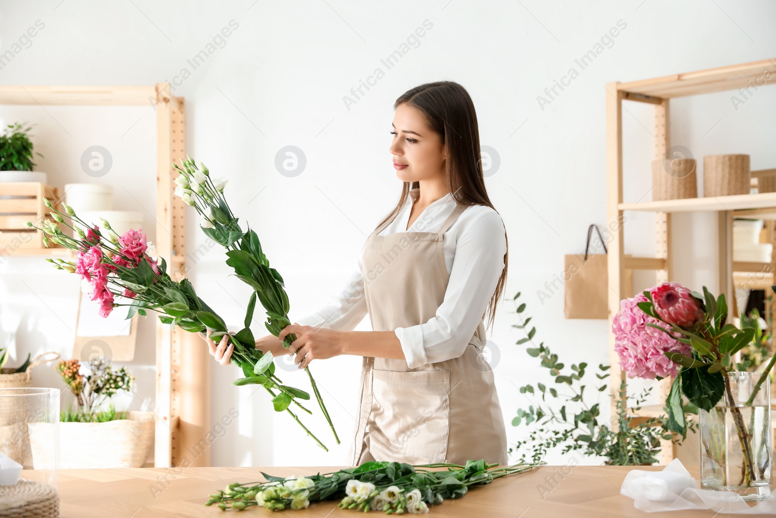 Photo of Florist making beautiful bouquet at table in workshop