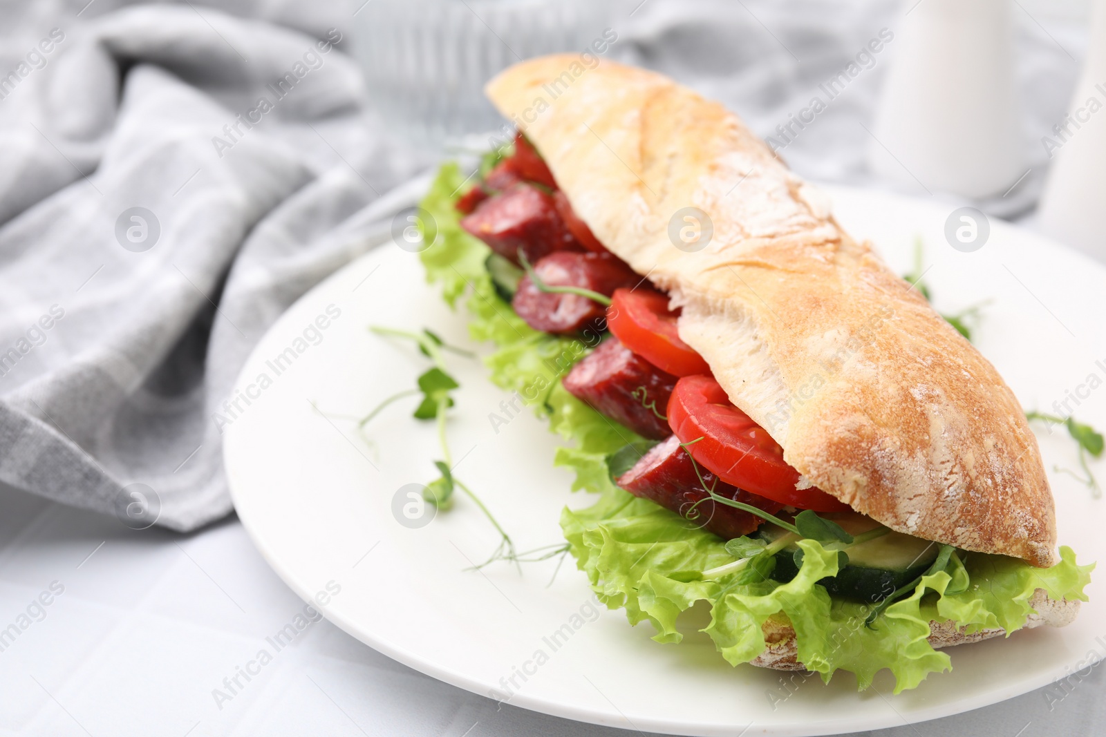 Photo of Delicious sandwich with sausages and vegetables on white table, closeup