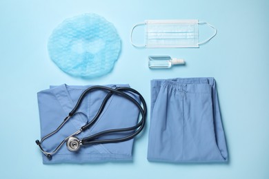 Photo of Flat lay composition with medical uniform and stethoscope on light blue background.
