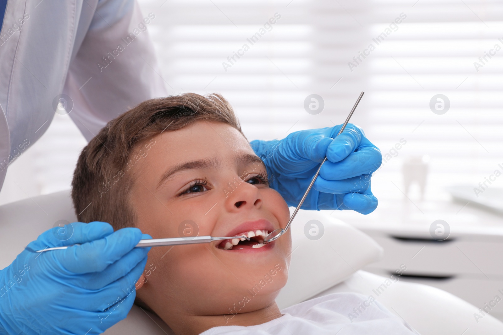 Photo of Dentist examining little boy's teeth in modern clinic