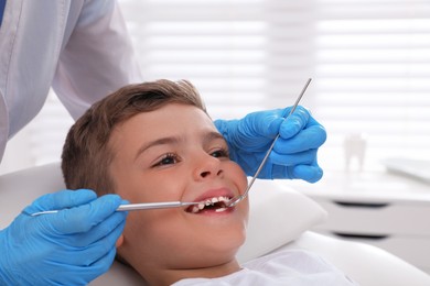 Photo of Dentist examining little boy's teeth in modern clinic