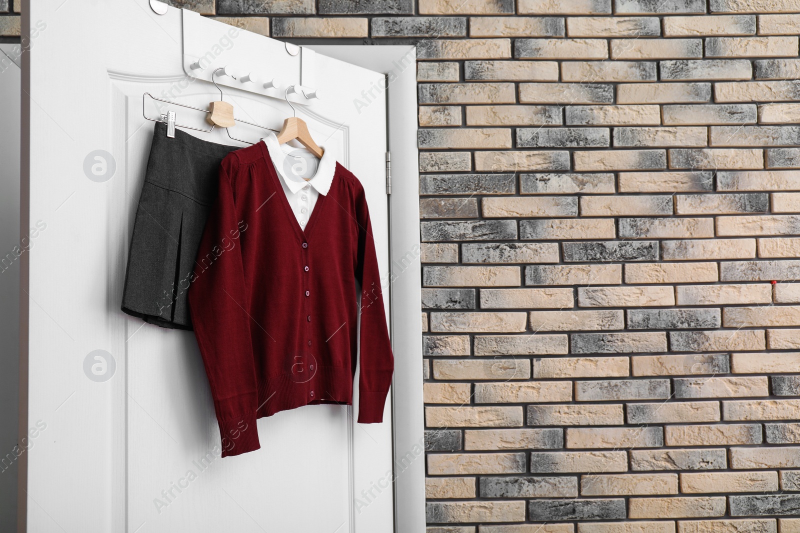 Photo of School uniform for girl hanging on white door